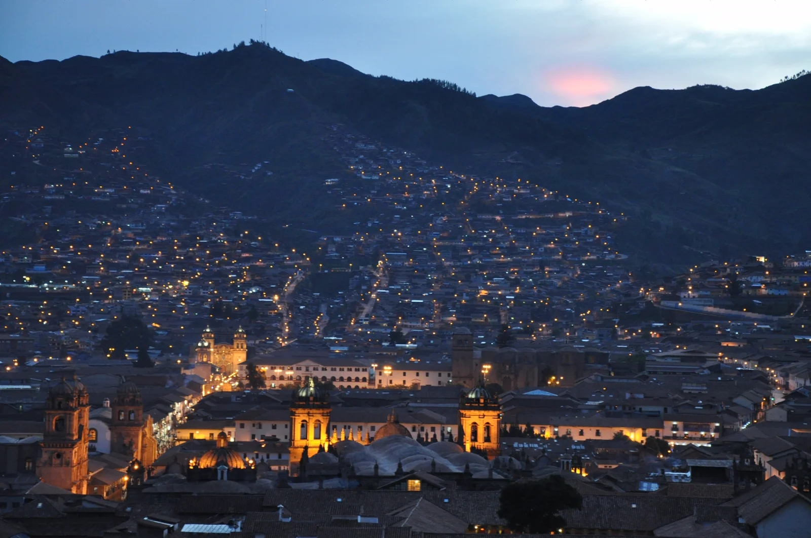 Cusco's Plaza de Armas at dusk, the cathedral and La Compañía lit above the square.