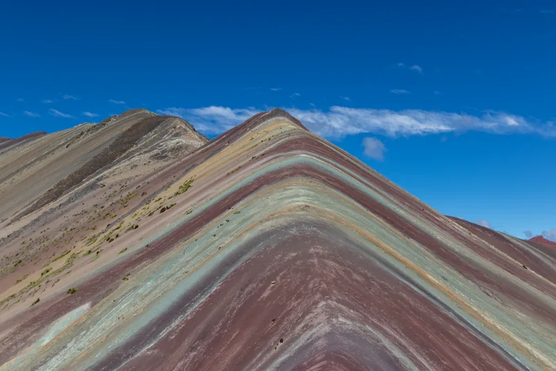 Vinicunca, the Rainbow Mountain, striped red and gold under a deep blue sky.