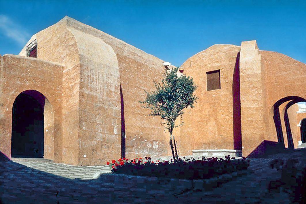 Empty courtyard of the Santa Catalina Monastery in Arequipa, with orange walls and a stone fountain